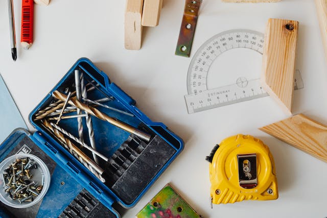 a bunch of tools, measuring tapes and screws on a workstation